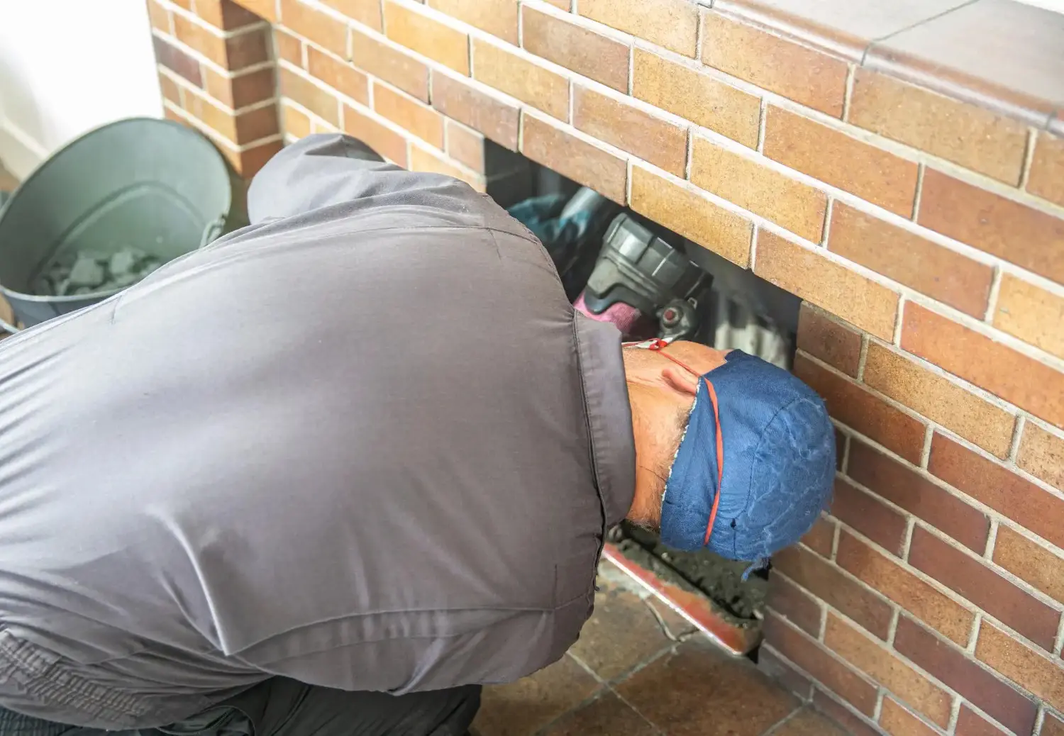 Chimney sweep cleaning inside brick fireplace.